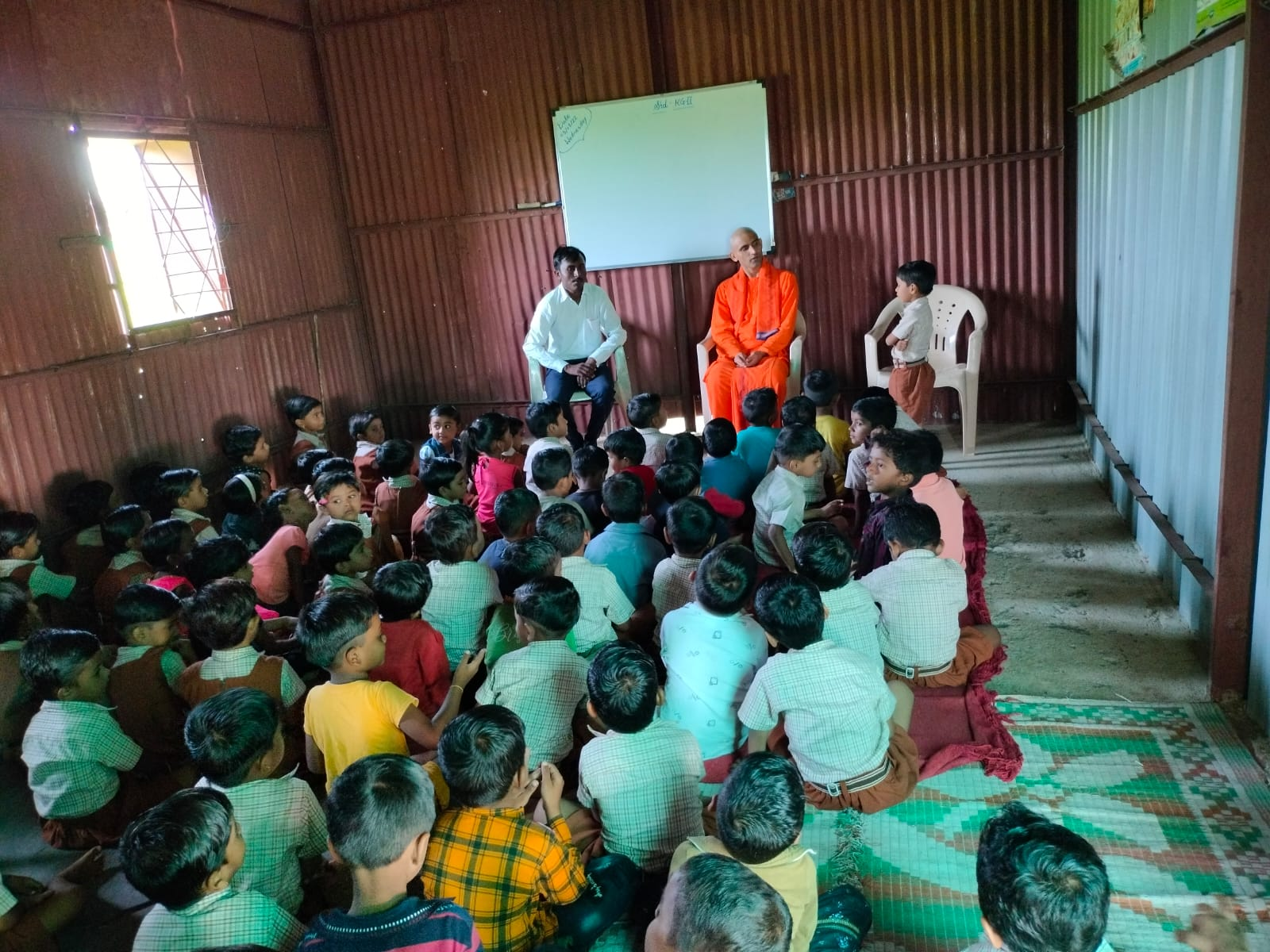 Schoolchildren attending a gathering with a monk and teacher at Chaitanya Education Society